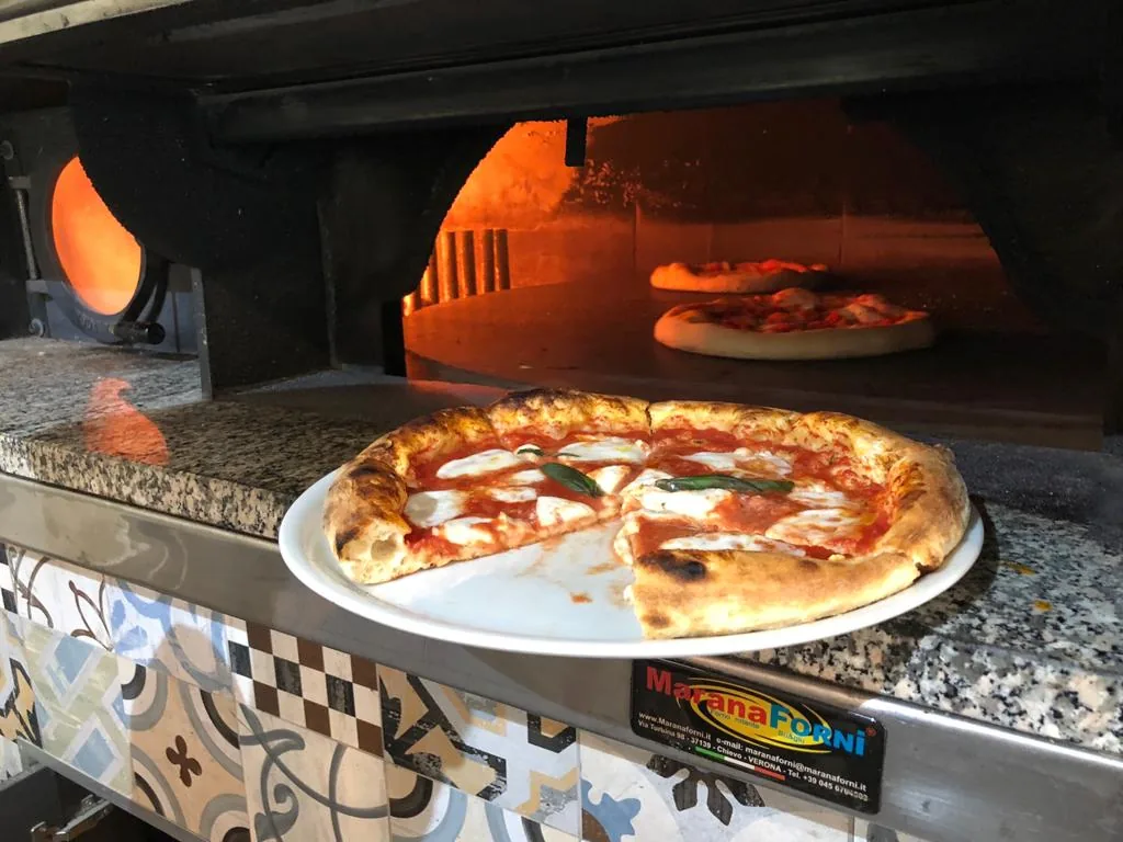 Il forno a legna con una pizza appena sfornata