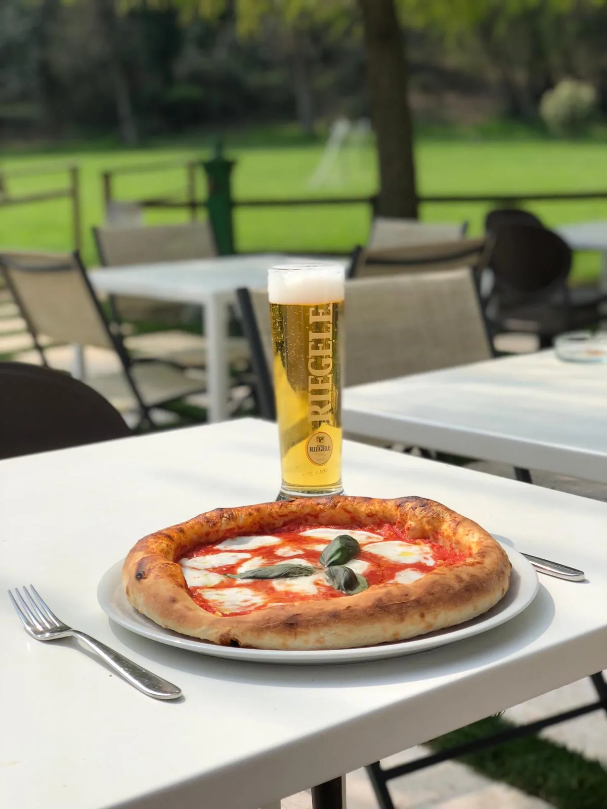 Pizza margherita dal cornicione alto servita ai tavoli in giardino